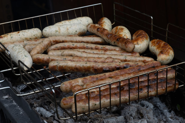在户外的烧烤架上烤香肠。烧烤。烤制食物:用木炭烤架炸或熏的食物把烤架翻过来，放上美味可口的香肠图片下载