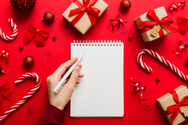 女人写圣诞做清单在笔记本上彩色背景与圣诞装饰图片下载