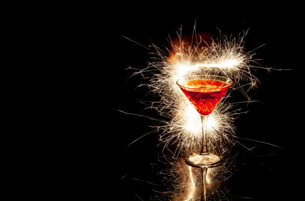 酒杯红色的鸡尾酒与火花反射在玻璃与黑色的背景图片下载