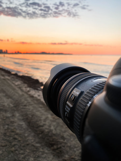 垂直特写的黑色相机镜头拍摄的海滩在日落图片下载