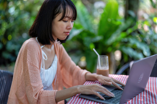 年轻女子在网上工作，从绿色花园和网上打电话给朋友和亲戚微笑图片下载
