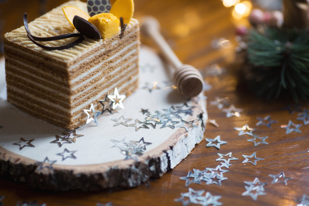 一块经典的蜂蜜蛋糕放在木架上，背景是美丽的圣诞散景。美味的食谱。庆祝的概念。2023年新年和圣诞节的概念。图片下载