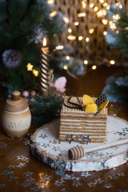 一块经典的蜂蜜蛋糕放在木架上，背景是美丽的圣诞散景。美味的食谱。庆祝的概念。2023年新年和圣诞节的概念。图片下载