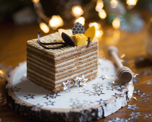 一块经典的蜂蜜蛋糕放在木架上，背景是美丽的圣诞散景。美味的食谱。庆祝的概念。2023年新年和圣诞节的概念。图片下载