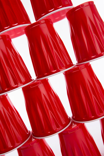 在白色背景下用红色一次性塑料杯制成的杯子金字塔的特写图片下载