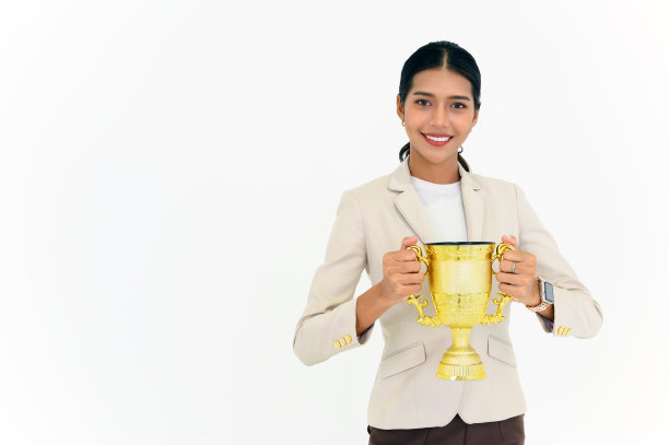 获奖女商人的肖像庆祝与奖杯奖在商业上的成功孤立的白色背景。成功员工手持金杯。看着摄像机。图片下载