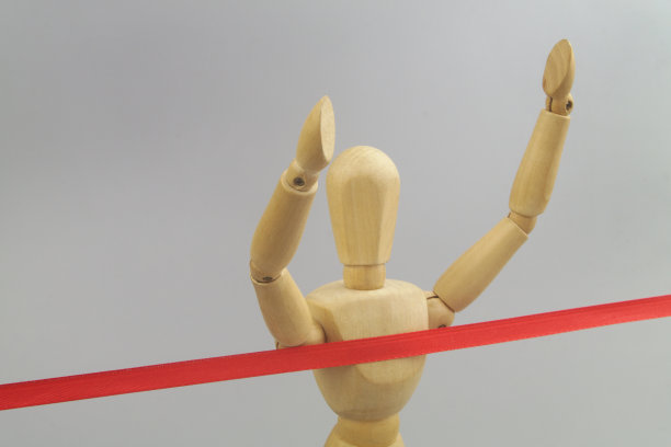 木制的人体模型和红色的终点线缎带在灰色的背景。图片下载