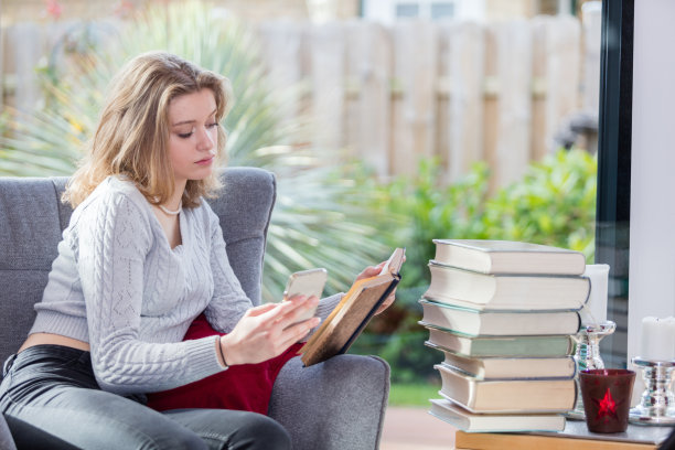 美丽的女孩在书和智能手机中阅读图片下载