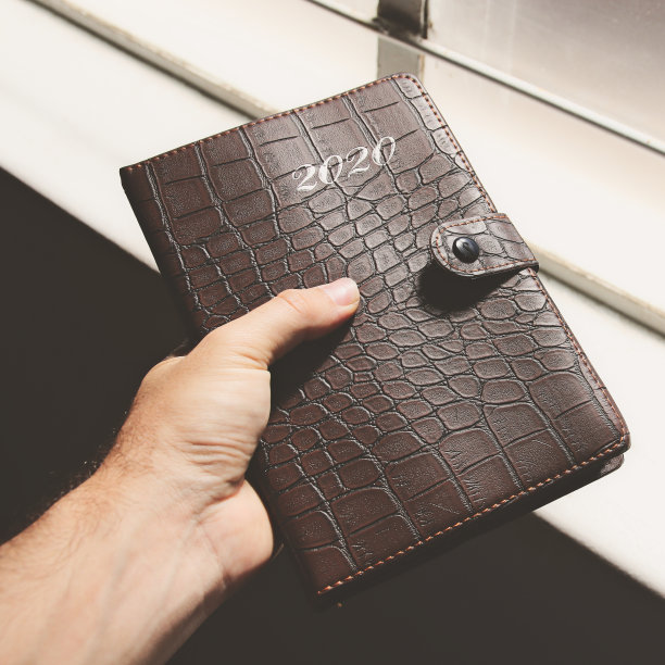 特写镜头，一只手拿着一个皮革封面的2020年计划图片下载