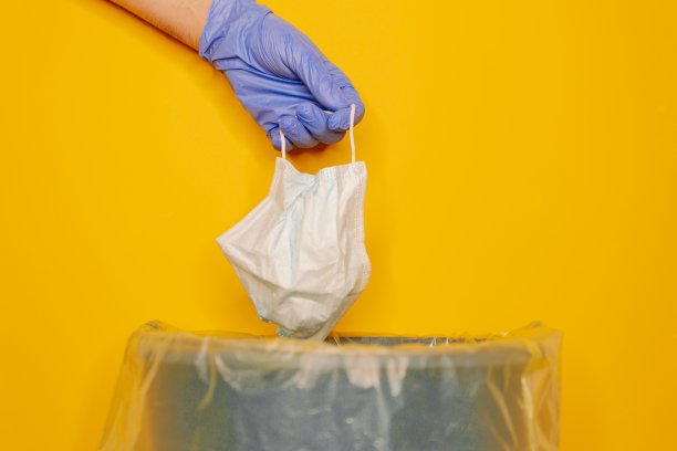 一个男人把医用口罩和医用手套放进垃圾桶的特写镜头图片下载