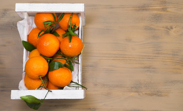 一盒成熟多汁的橘子放在木制背景上图片下载