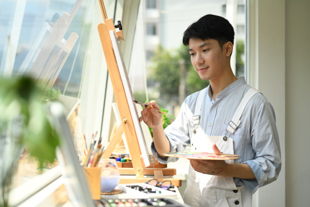 聚精会神的亚洲人在艺术工坊窗边的画布上作画。休闲活动、创作爱好和艺术观念。图片下载