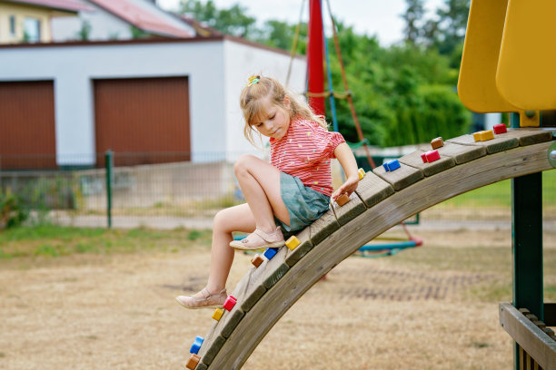 夏天的一天，小女孩在操场上爬。快乐勇敢的学龄前儿童享受运动和儿童活动。图片下载