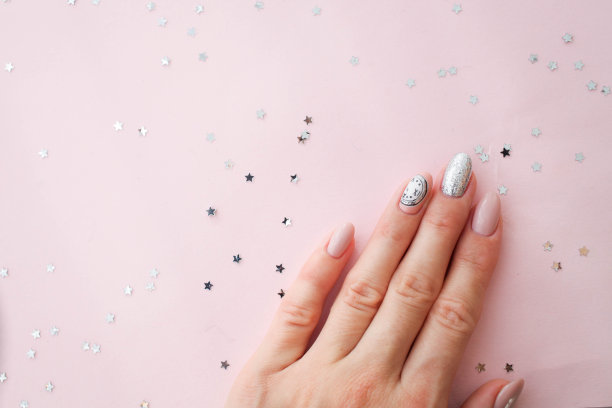 美丽的女性手与粉红背景的圣诞指甲设计。指甲设计，带有编钟图案的美甲。亮片。虫胶,凝胶波兰。图片下载
