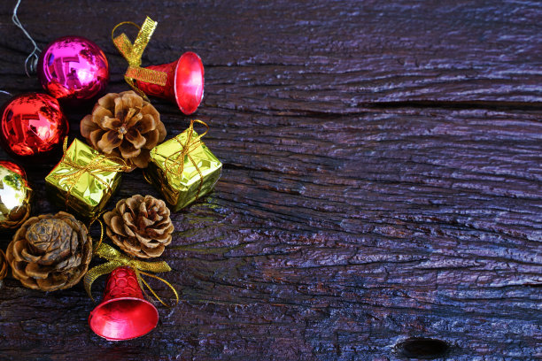 新年和圣诞礼物主题装饰在木制背景，由一个金色礼品盒组成。干松果和小铃铛为设计腾出了空间图片下载