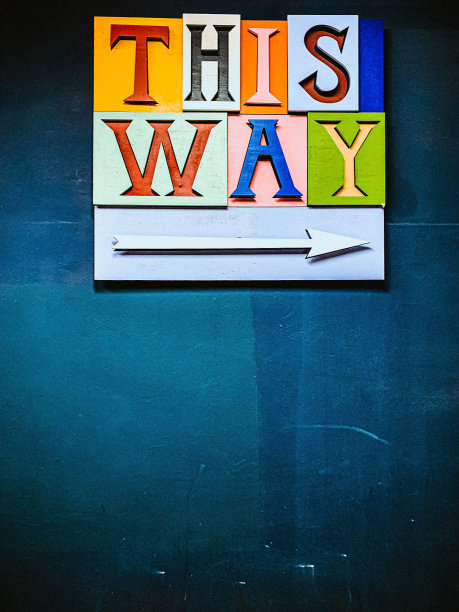 特写的彩色THIS WAY和箭头指向右边的蓝色背景图片下载