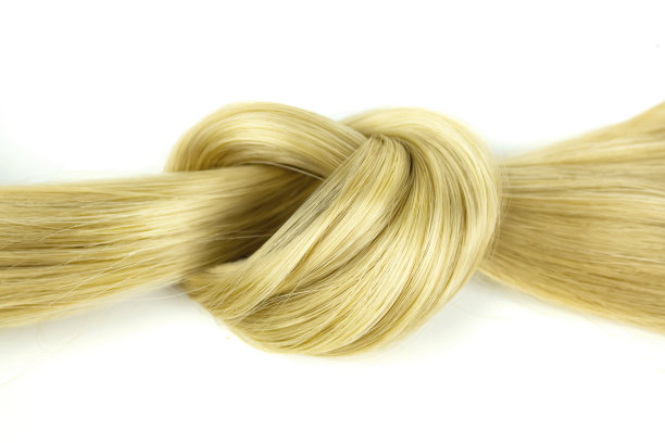 白色背景下的金色自然头发。俯视图，一缕蜜汁般的金发。白色背景上的卷发。图片下载