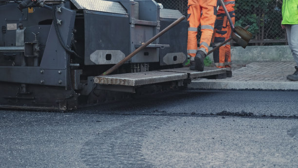 铺路机铺路工程沥青铺路机，工人穿着防护服操作图片下载