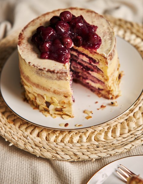 白色盘子上切好的樱桃蛋糕的垂直镜头图片下载