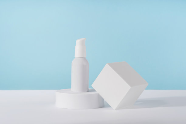 化妆品霜金属泵瓶模型在蓝色背景上的白色几何底座讲台。无品牌乳液美容产品包装。产品演示模型图片下载