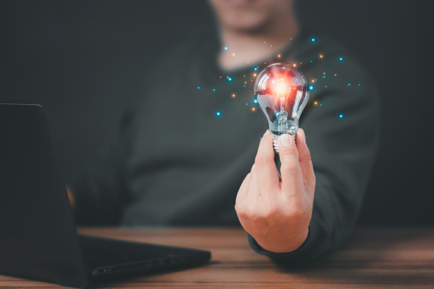 拿着灯泡的人一边在电脑上工作一边用技术创新和创造力思考和创造新的想法灵感来自在线技术，创新。图片下载