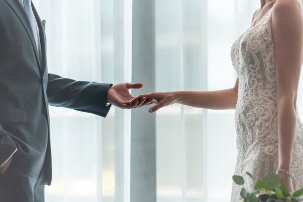 新娘和新郎在白色窗帘前牵着手的特写镜头图片下载