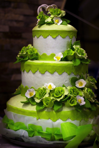 垂直特写，一个装饰精美的高高的蛋糕，上面有绿色和白色的花朵图片下载