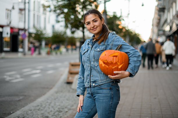肖像微笑的妇女拿着南瓜或杰克o灯笼，看着相机图片下载