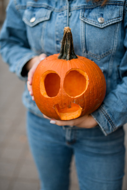 选择重点美丽明亮的橙色南瓜雕刻可怕的脸在女性的手图片下载
