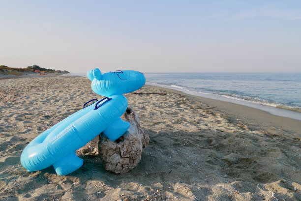 在荒芜的沙滩上充气的蓝色河马。暑假的概念。图片下载