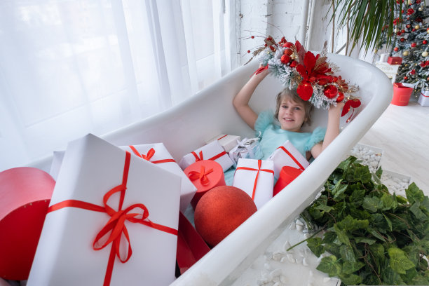 少女在装满礼品盒的浴缸里泡澡，圣诞节概念图片下载