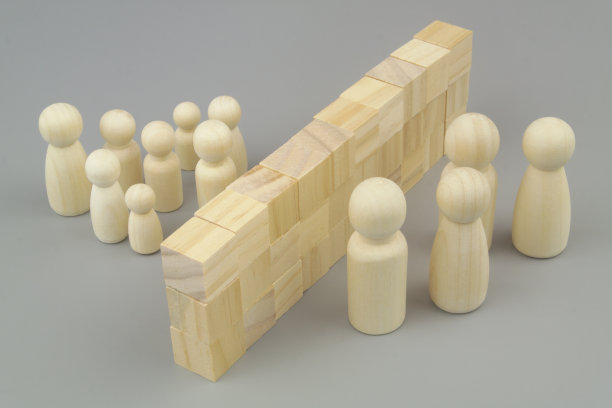 父母和孩子的木制人物被用木块做成的墙隔开。图片下载