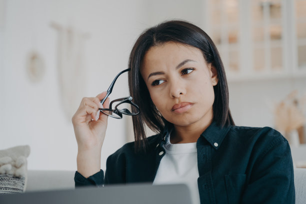 困惑的女商人在笔记本电脑上处理商业项目，摘下眼镜，思考问题图片下载