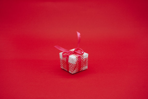 小白粉礼品盒与粉红色丝带。圣诞礼物盒子。孤立在红色背景上图片下载