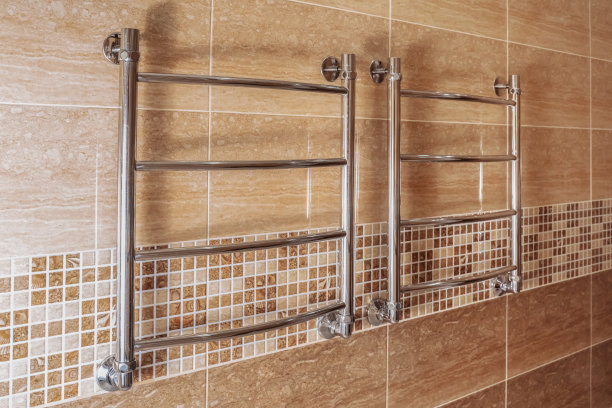 浅棕色墙壁上的现代加热毛巾架。图片下载