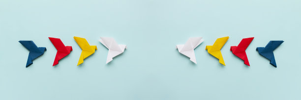 两组纸折纸鸽子，白、黄、红、蓝四色，飞向光背景，16:9图片下载