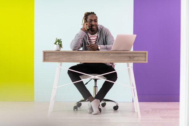 微笑的年轻非洲人自由职业者使用笔记本电脑和智能手机在家里学习在线工作图片下载