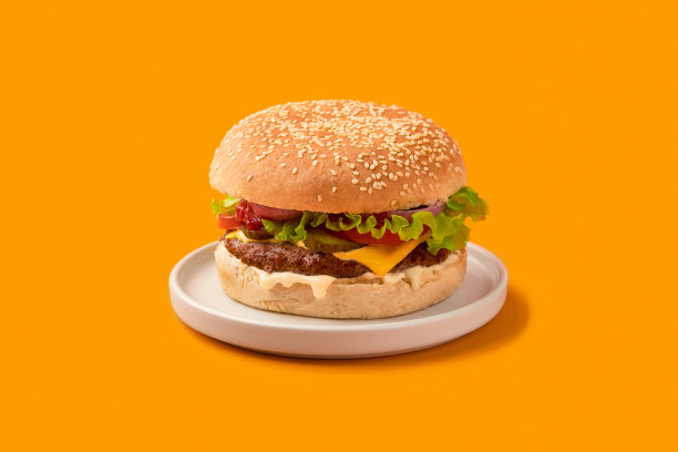 新鲜可口的汉堡在橙色背景。芝士汉堡配牛肉、西红柿、咸菜、生菜和洋葱图片下载