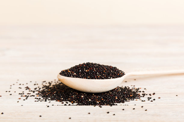 藜麦种子在勺子上的彩色背景。小勺子里的健康金瓜。健康的超级食物图片下载