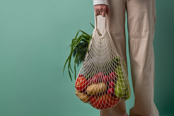 妇女拿着装着蔬菜和草药的网袋。图片下载