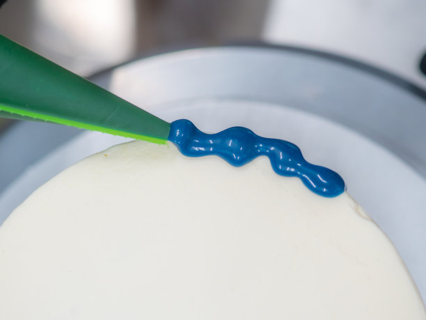 近手糕点厨师设计师顶部的霜白色蛋糕与蓝色滴填充袋图片下载