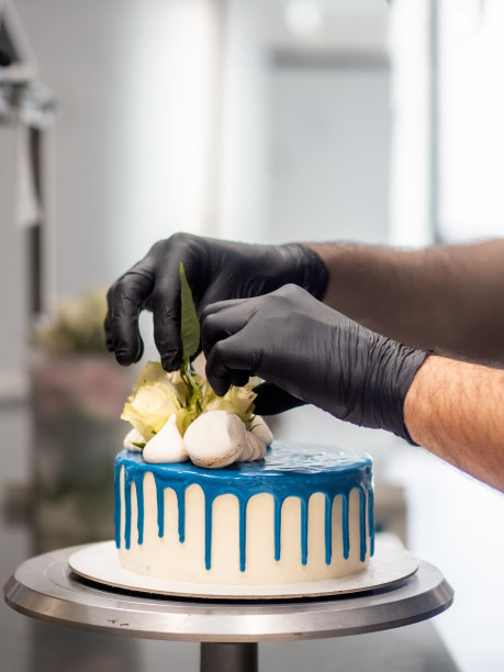 糕点师用马卡龙蛋白霜和真正的花朵装饰蓝白色的磨砂蛋糕图片下载