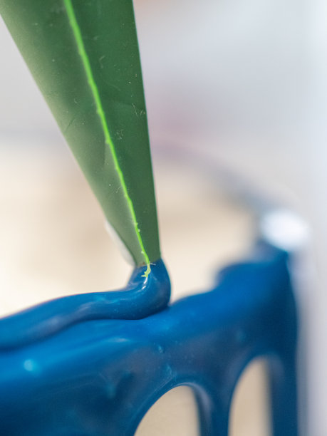 近手糕点厨师设计师顶部的霜白色蛋糕与蓝色滴填充袋图片下载