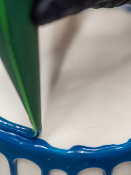 近手糕点厨师设计师顶部的霜白色蛋糕与蓝色滴填充袋图片下载