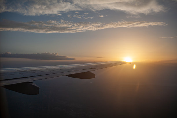 飞机飞行。通过照明器看到飞机的机翼和地面图片下载