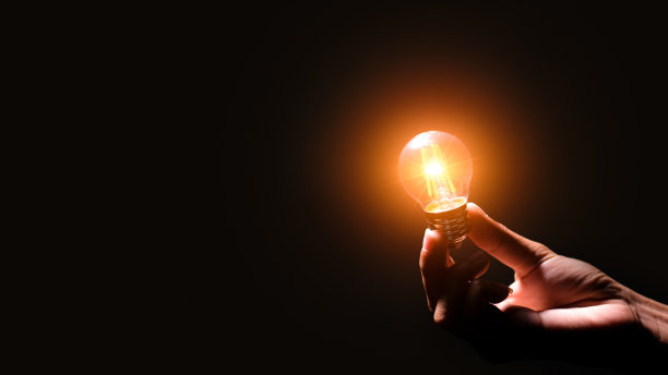 手持灯泡发光与连接线的创造性思维想法和创新概念。可再生能源的概念可持续，资源和环境图标在黑色背景。图片下载
