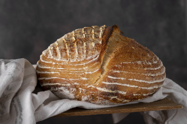 自制的整圆面包在黑暗的背景。家庭烘焙的概念。图片下载