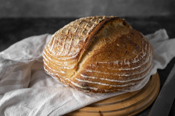 自制的整圆面包在黑暗的背景。家庭烘焙的概念。图片下载