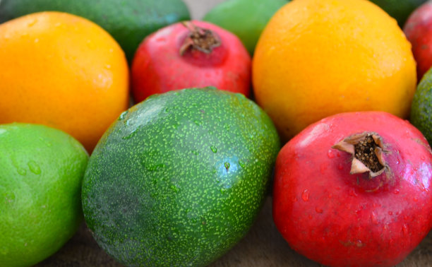 各种新鲜成熟的热带水果作为背景。鳄梨、橙子、酸橙和石榴。异域水果，纯素食品或饮食概念。图片下载