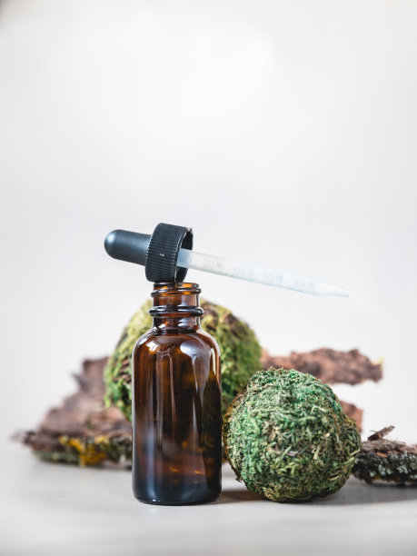 打开的棕色玻璃滴管瓶与移液管米色背景与树皮和苔藓。天然美容水疗产品。化妆品的包装。模拟。图片下载